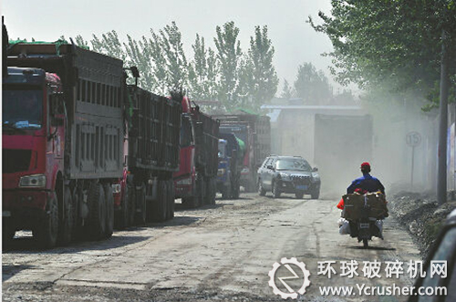 　21日上午，經(jīng)十東路雞山村西側的一條無名路上，大貨車往來不絕，拉著碎石子的貨車通過時塵土飛揚。